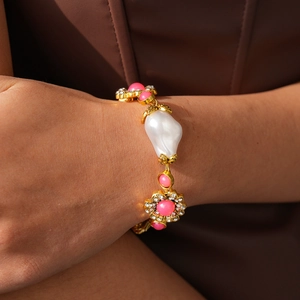 Detail of baroque pearl bracelet with pink stones and floral crystals on golden base