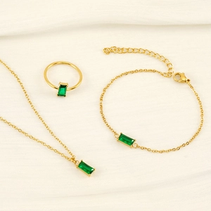 Set gioielli placcati oro 18K con pietre rettangolari verde smeraldo su tessuto bianco piegato