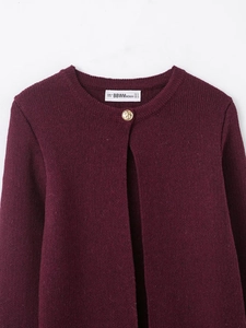 Detailed close-up of a wine red knit cardigan with a single decorative gold button