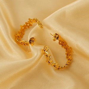 Golden hollow star-shaped C-style hoop earrings on elegant silk background