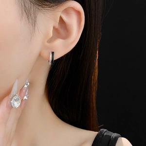 Close-up of geometric black zircon hoop earring worn by a model with elegant nails