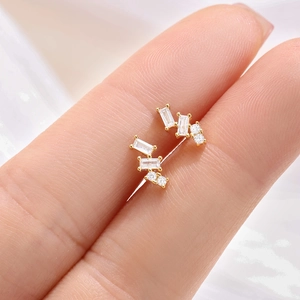 Macro shot of gold square stud earrings with clear rectangular and round zircon stones