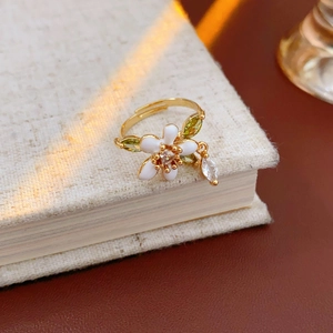 Dettaglio ravvicinato di un anello a fiore dorato vintage con smalto su libro in lino