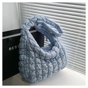 Detail of light blue quilted puffer shoulder bag with a soft pleated cloud texture