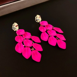Close-up of pink acrylic petal earrings with golden irregular metal studs and matte finish