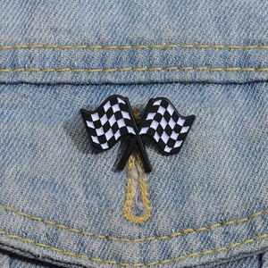 Detailed view of metal racing checkered flags enamel pin pinned to blue denim fabric