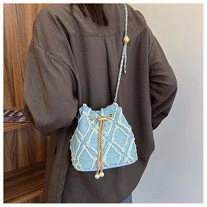 Detail of light blue denim bucket bag featuring diamond embroidery and pearl accents