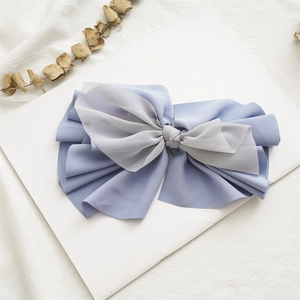 Detailed close-up of a large fabric bow hair clip with blue and gray gradient layers