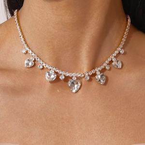 Close-up of golden tennis necklace with sparkling heart-shaped zircon pendants on neck