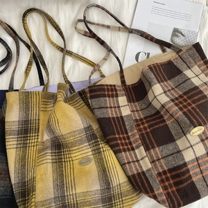 Detail view of large wool tote bags in yellow and brown plaid with metal logo
