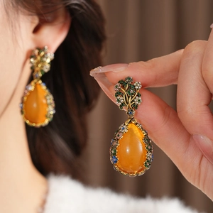 Macro shot of vintage floral drop earrings with amber teardrop gems and colorful rhinestones