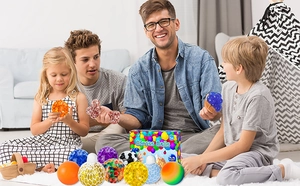 Family playing with varied stress balls including mesh and bead types on a home rug