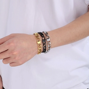 Three men's cuban link bracelets in gold black and silver on a male wrist detail