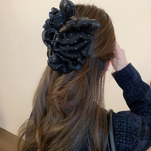 Detail of a large black mesh bow hair claw with white polka dots on a woman's hair
