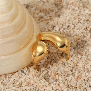 Irregular organic 316 stainless steel gold ring displayed on beach sand with a seashell