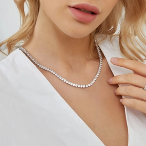 Close-up of sparkling 3-claw silver tennis necklace with clear cubic zirconia on neck