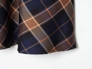 Close-up of blue and brown plaid fabric showing high-quality stitching and twill texture