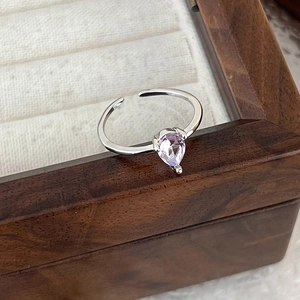 Close-up of silver ring featuring a teardrop purple zircon in a wooden jewelry box