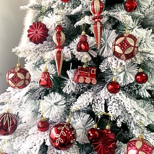 Weihnachtsbaumschmuck-Set mit roten und goldenen Kugeln und Sternen in einer Schneeszene