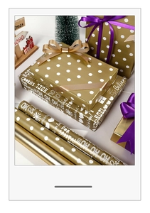 Detail of Christmas gift wrapping paper featuring gold dots and holiday typography print