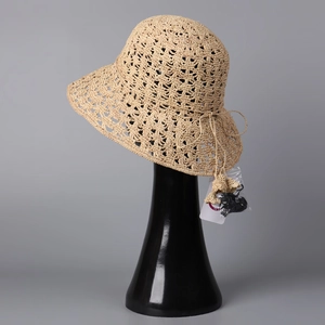 Détail d'un chapeau de soleil en paille tissé main avec motif crocheté beige et nœud