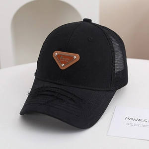 Dettaglio del cappellino mesh nero con patch triangolare e texture dell'orlo usurata