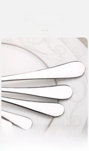 Close-up of stacked stainless steel ice tongs handles on a white ceramic plate