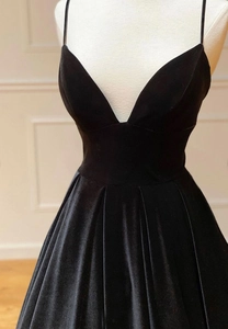 Detail of elegant black velvet evening dress with slim straps and plunging V-neckline