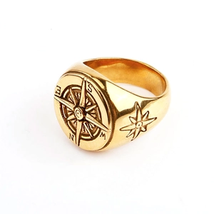 Macro detail of a gold compass signet ring with N S E W engravings on a white background