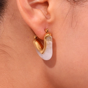 Close-up of 18K gold triangular acrylic earrings worn by a model on the ear