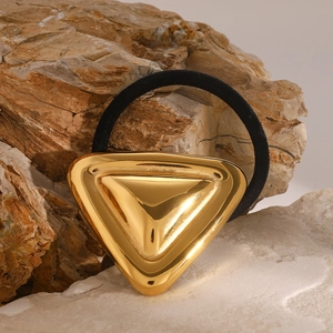 Macro view of a mirror-polished gold triangular charm on a black elastic hair tie