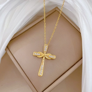 Collana croce intrecciata dorata di lusso con zirconi su un portagioie color beige