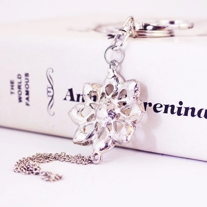 Vintage silver flower keychain with pearls and crystals on a white book backdrop