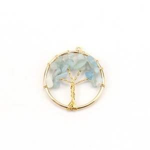 Detail of tree of life pendant with golden wire wrap and light blue crystal stones