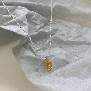 Macro view of 925 silver beaded chain with a vintage gold portrait coin pendant