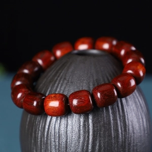 Detailed close-up of polished high-density purple sandalwood barrel beads on a silk cord