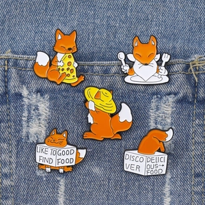 Set of five cute orange fox enamel pins displayed on denim pocket showing various poses