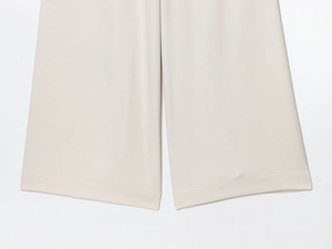 Close-up of beige wide-leg trousers showing smooth fabric drape and precise hem stitching