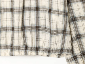 Vista dettagliata della camicia a quadri con focus sulla trama del tessuto e cuciture