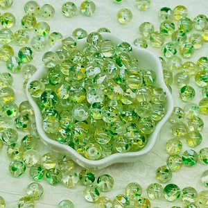 Macro shot of 8-10mm green glass flowered beads in a white bowl for DIY jewelry