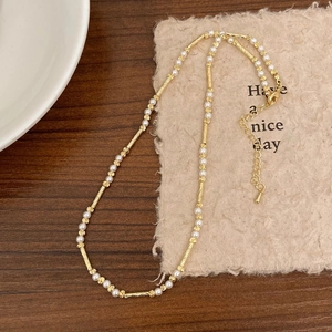 Detail einer eleganten Perlenkette mit Goldperlen und verstellbarer Verlängerungskette