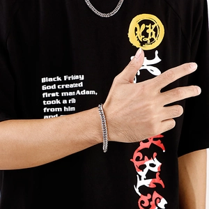 Makroaufnahme eines silbernen Panzerarmbands aus Edelstahl am männlichen Handgelenk