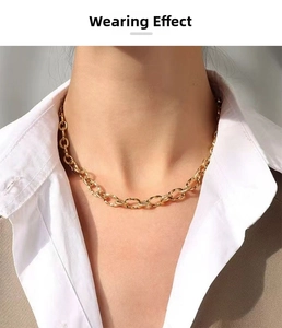 Detailed view of a thick gold oval link chain necklace worn with a white shirt and blazer