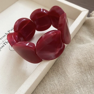 Macro shot of dark red acrylic resin beaded bracelet on a neutral textured linen background