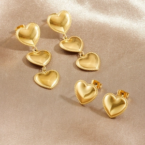 Gold-plated stainless steel heart drop earrings with beaded texture on silk background