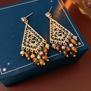 Detailed macro view of vintage gold hollow geometric earrings with brown beaded tassels