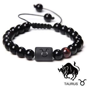 Macro view of woven Taurus constellation bracelet with black beads and tiger eye stone