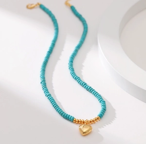 Exotic turquoise beaded necklace featuring a golden heart pendant on white geometric blocks
