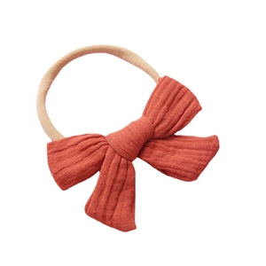 Muslin cotton baby headband with terracotta textured bow on a beige nylon strap