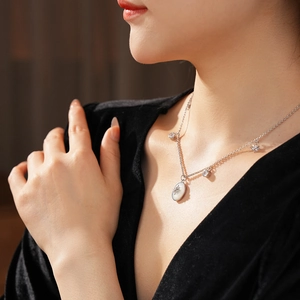 Dettaglio di una collana argentata con ciondolo in madreperla su un top di velluto nero